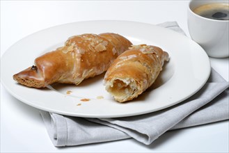 Almond croissant on plate with coffee cup