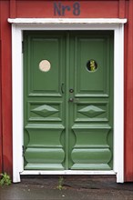 Traditional green wooden door with ornaments in red wooden house in Vimmerby