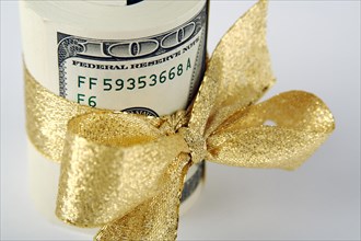 One hundred dollar bills wrapped in gold ribbon