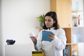 Pharmacist with medicine in a pharmacy working with modern technology and smock