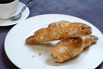 Almond croissant on plate with coffee cup