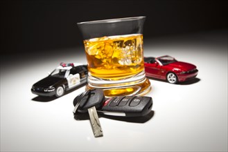 Highway patrol police and sports car next to alcoholic drink and keys under spot light