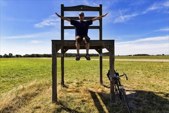 Cyclist sits on oversized chair in a meadow