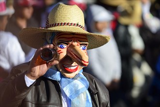 Mask of a man with a beer bottle at the parade on the eve of Inti Raymi