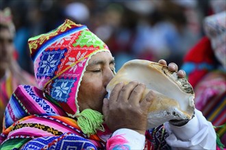 Indigenous man blows conch shell during parade on eve of Inti Raymi