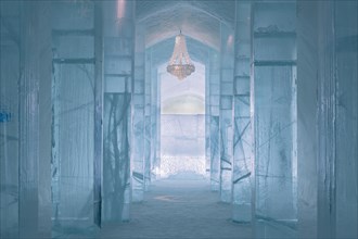 Long corridor with table and chandelier made of ice in the ice hotel of Jukkasjaervi