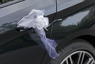 White bow on the door handle of a black car