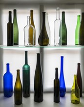 Decoration of colorful wine bottles on a shelf at the window