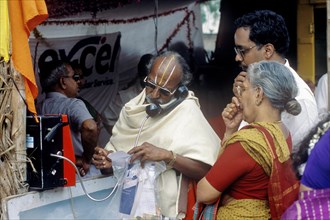 Ein Brahmane spricht am oeffentlichen Festnetztelefon waehrend des Thyagaraja Aradhana Festivals in Thiruvaiyaru in der Naehe von Thanjavur