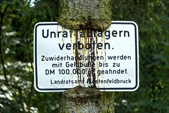 Sign Unrat ablagern verboten at the tree trunk