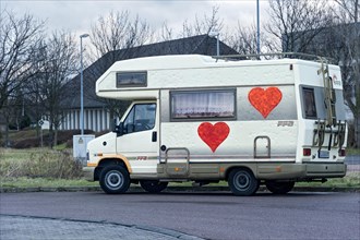 Motorhome of a prostitute with painted big red hearts on parking lot on the outskirts of town