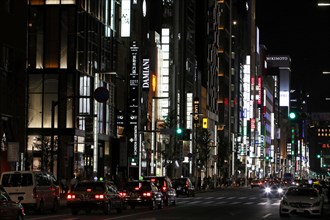 Illuminated street with neon lights and cars in traffic in Ginza district