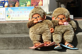 Two large Monchichi puppets on the stairs in front of a souvenir shop