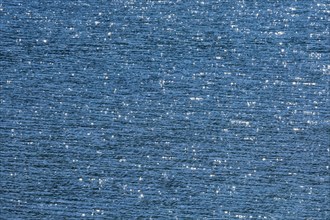 Sunbeams reflect glittering on the water surface of the Vierwaldstaettersee and form an abstract pattern