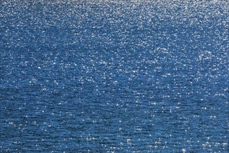 Sunbeams reflect glittering on the water surface of the Vierwaldstaettersee and form an abstract pattern