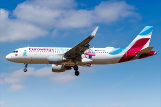 A Eurowings Airbus A320 with the registration OE-IQD and the special livery Holidays lands at London Heathrow Airport