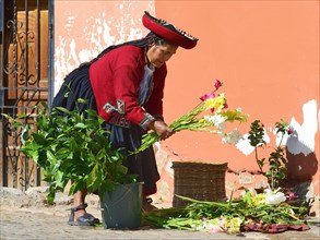 Indigenous woman in traditional traditional costume with bouquet of gladioli