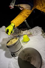 Man cooking with a camping stove in the snow