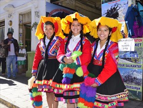 Three young indigenous woman in colorful costumes in the old town
