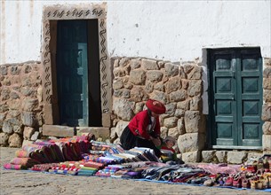 Indigenous woman in traditional traditional costume with small child selling souvenirs in front of her house