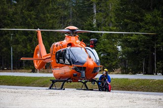 A flight rescuer of the Bergwacht Bayern kneels next to the rescue helicopter Christoph 14