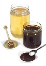 Molasses and honey pots against white background