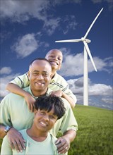Happy african american family and wind turbine with dramatic sky and clouds
