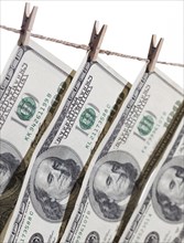 Hundred dollar bills hanging from clothesline on a white background