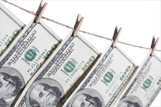 Hundred dollar bills hanging from clothesline on a white background