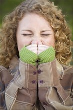 Pretty young woman sneezing outdoors