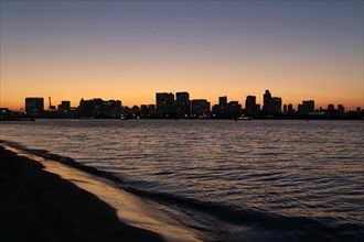 View from Odaiba Beach to Tokyo Bay with skyline silhouette at dusk