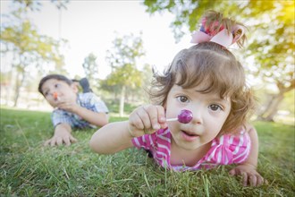 Cute baby girl and brother with lollipops in the park