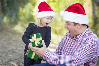 Happy father giving young daughter A christmas gift outdoors