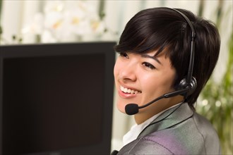 Attractive young woman smiles wearing headset near her computer monitor