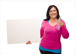Attractive middle aged hispanic woman in workout clothes with water bottle and blank white sign against a white background