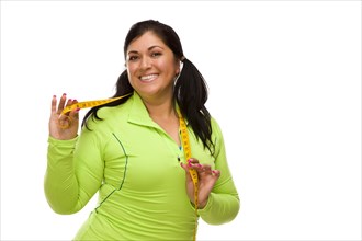 Attractive middle aged hispanic woman in workout clothes showing off her tape measure against a white background