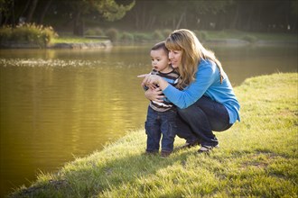 Happy mother and baby son looking out at the pretty lake