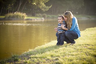 Happy mother and baby son looking out at the pretty lake