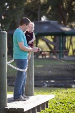 Cute young boy and loving dad fishing on the lake dock