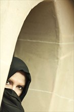 Cautious islamic woman in a window pane wearing traditional burqa or niqab