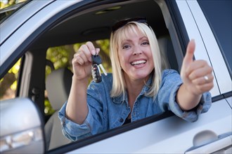 Attractive happy woman in new car with keys