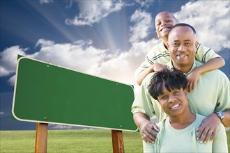 Attractive african american family in front of blank green road sign ready for your own message