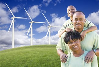 Happy african american family and wind turbine with dramatic sky and clouds