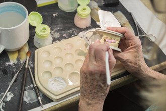 Female dental technician applying porcelain to A 3D printed implant mold in the lab