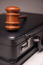 Gavel and black briefcase on gradated background with selective focus