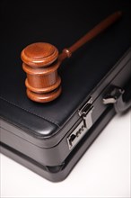 Gavel and black briefcase on gradated background with selective focus