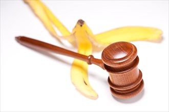 Gavel and banana peel on gradated background with selective focus