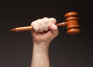 Male fist holding wooden gavel on a grey background