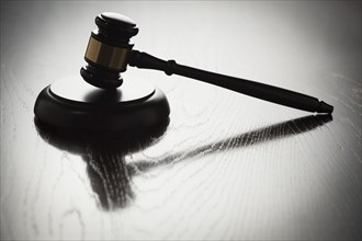 Dramatic gavel silhouette on reflective wood surface