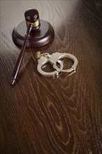 Gavel and pair of handcuffs on wooden table